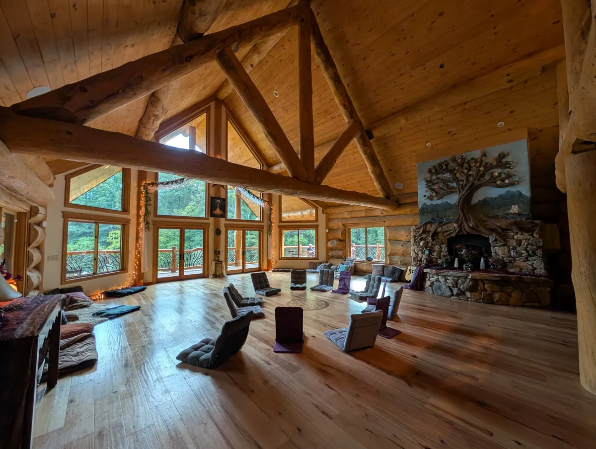 The workshop room in the lodge, with floor chairs set out on a wooden floor and tall windows looking into the trees
