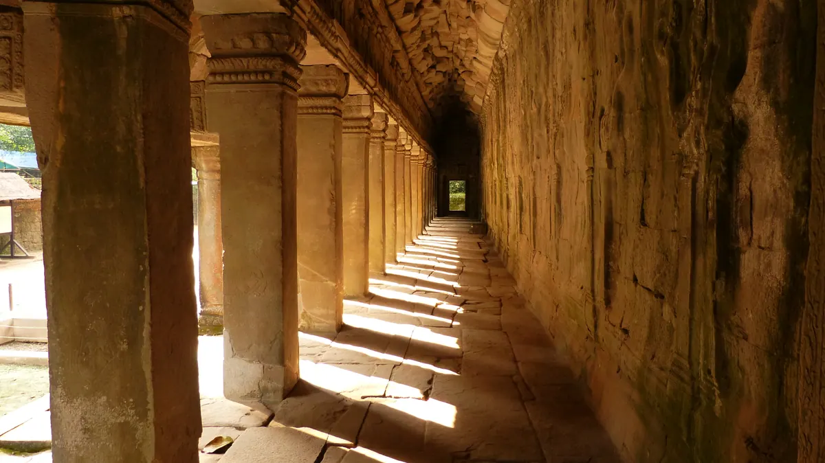 Warm light repeating through a long stone colonnade at Angkor