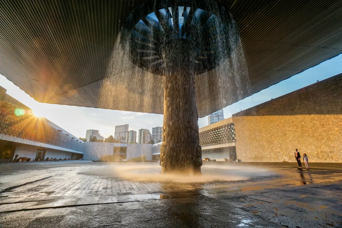 Water falling from the umbrella fountain in the courtyard of the National Museum of Anthropology, with the sun breaking under its canopy
