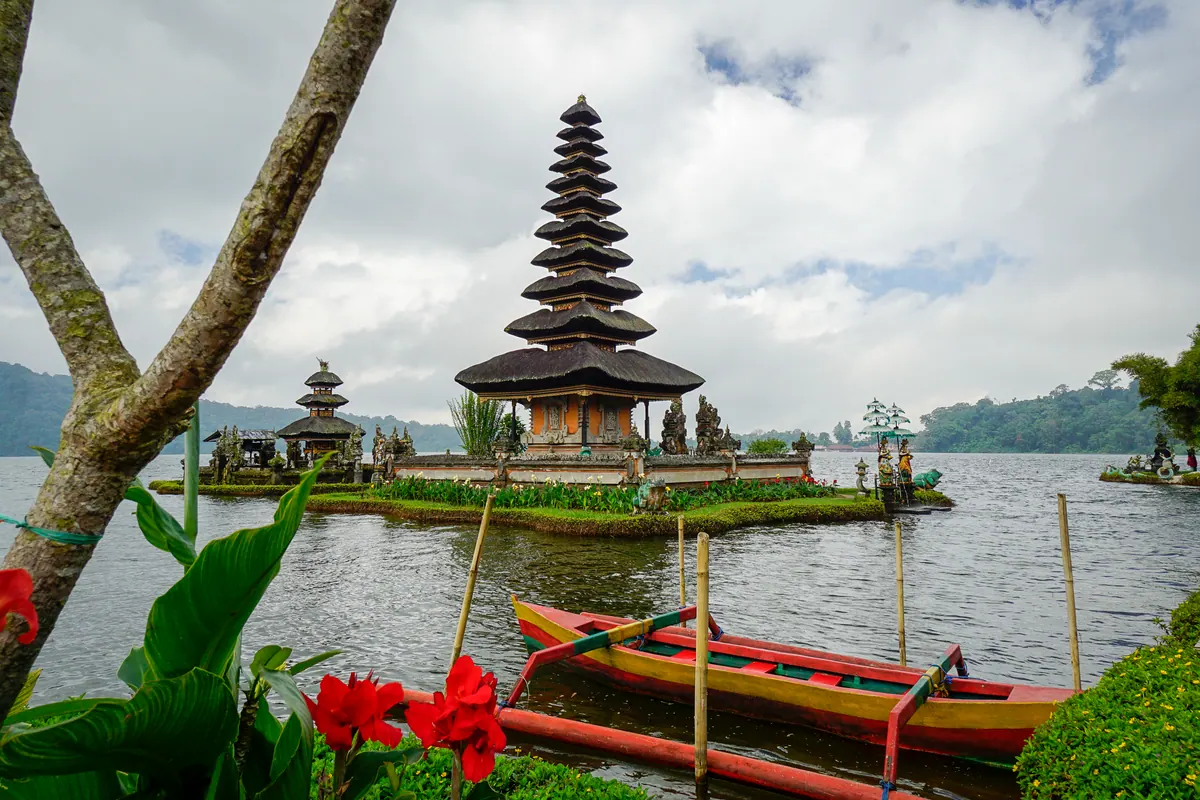 The tiered lake temple of Pura Ulun Danu Beratan across the water, with a painted canoe moored in the foreground