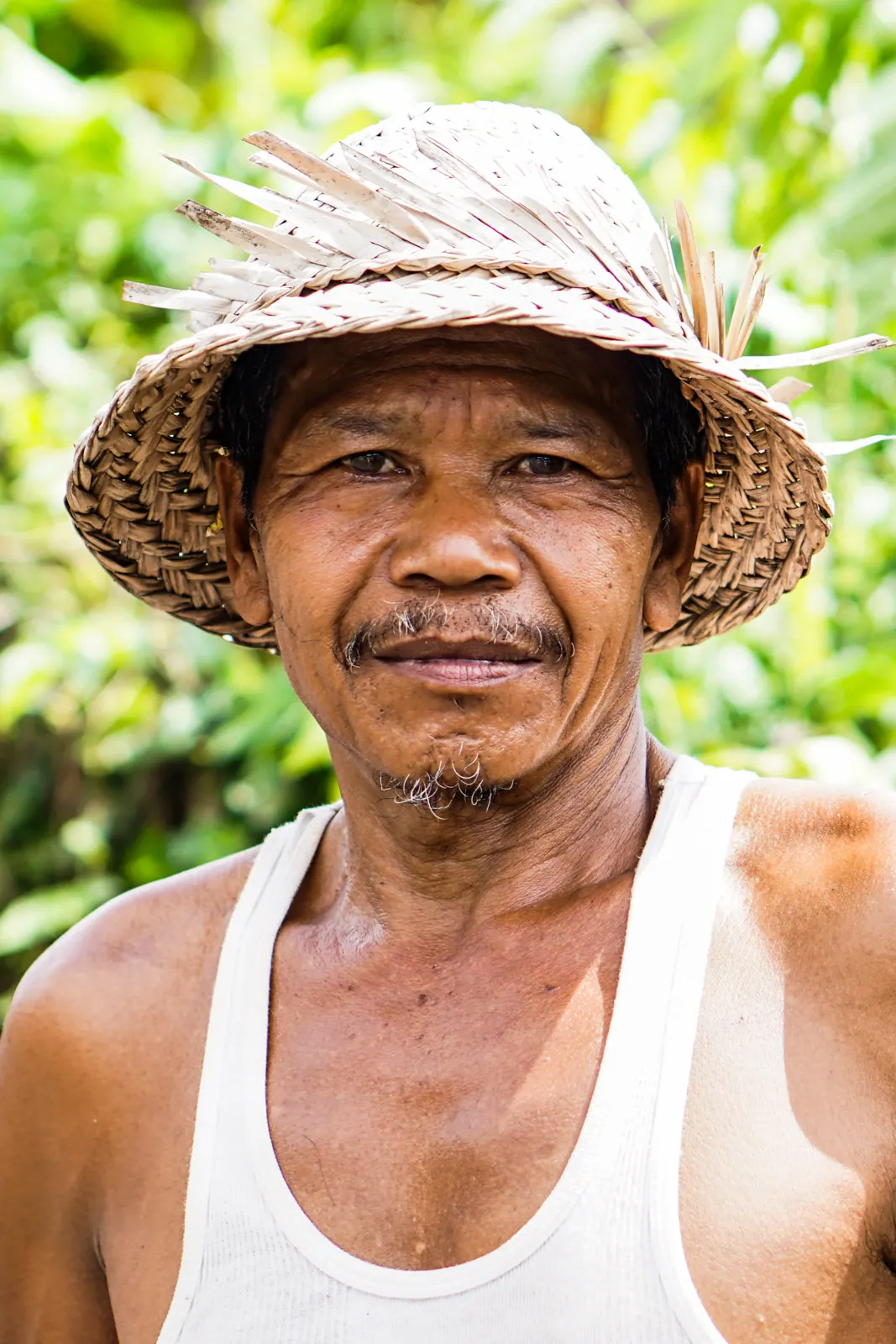 A Balinese man in a straw hat smiling into the camera