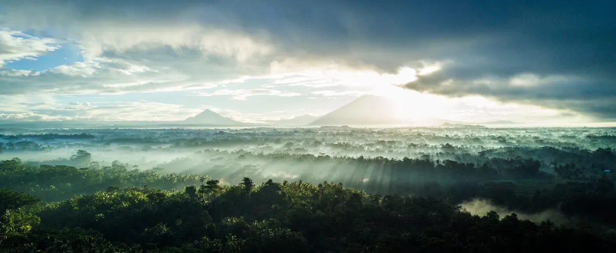 Bali's volcanoes rising above the clouds at sunrise, seen from the air