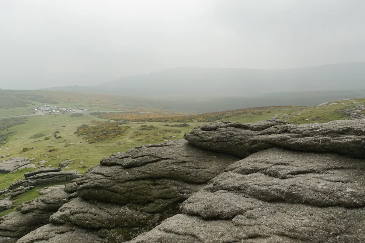 Weathered granite tors disappearing into fog across a high English moor