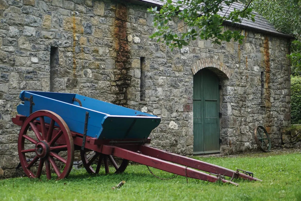 An old blue farm wagon against a weathered brick wall, Bunratty, Ireland