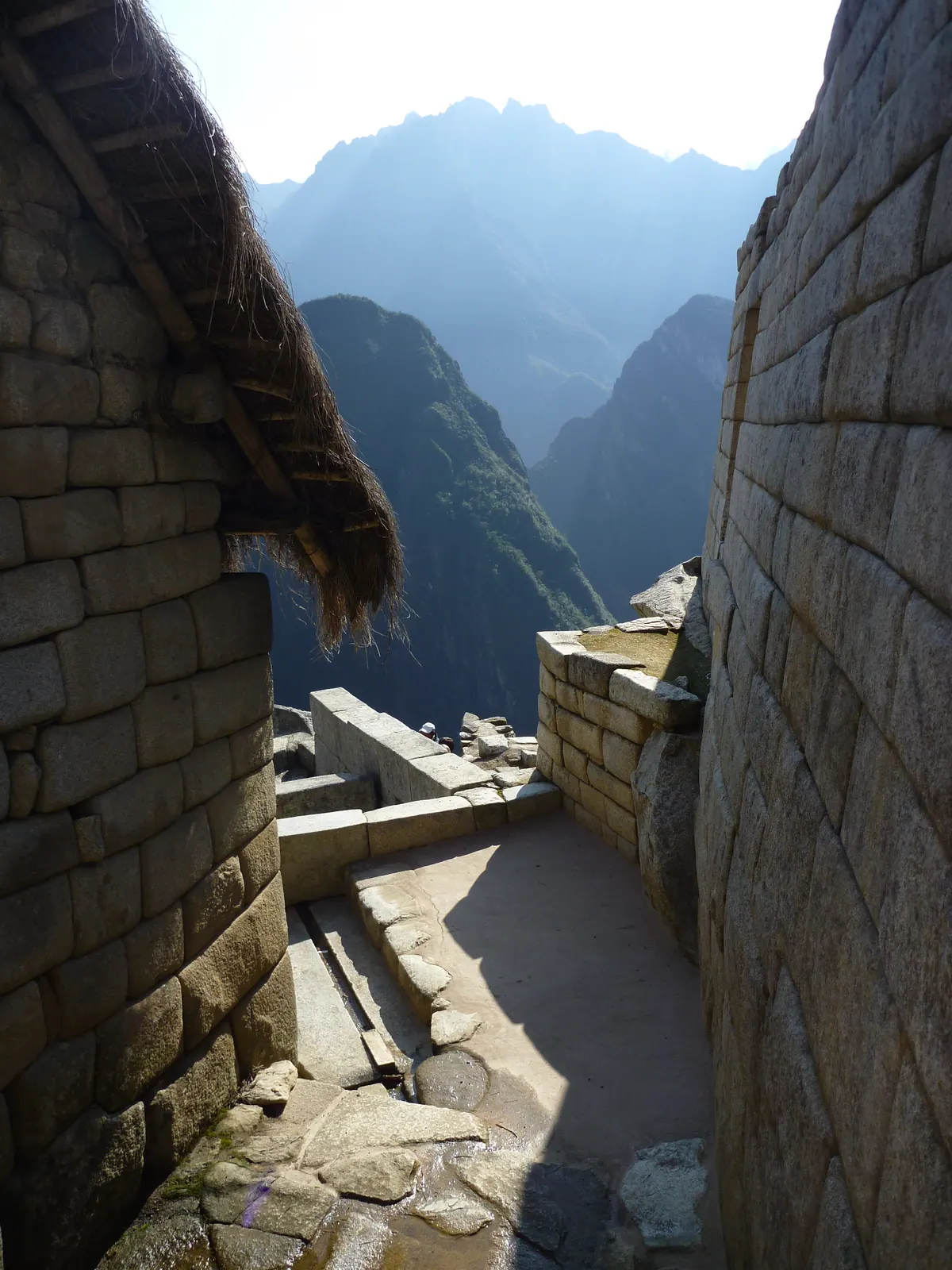 Machu Picchu and its mountain peaks glimpsed through a narrow stone passage