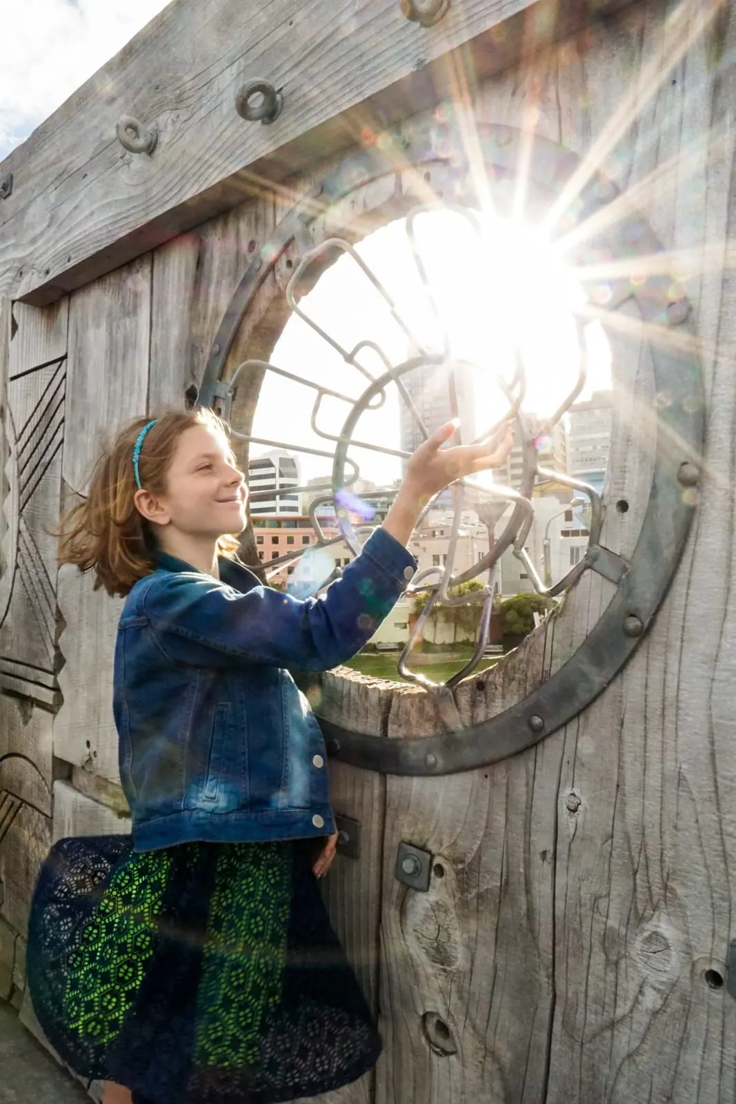 A child reaching toward the sun through a round window