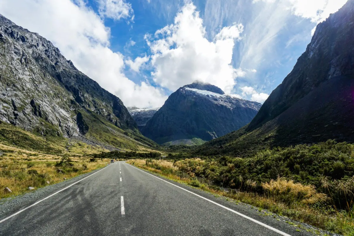 An empty road curving toward the peaks of Milford Sound, New Zealand