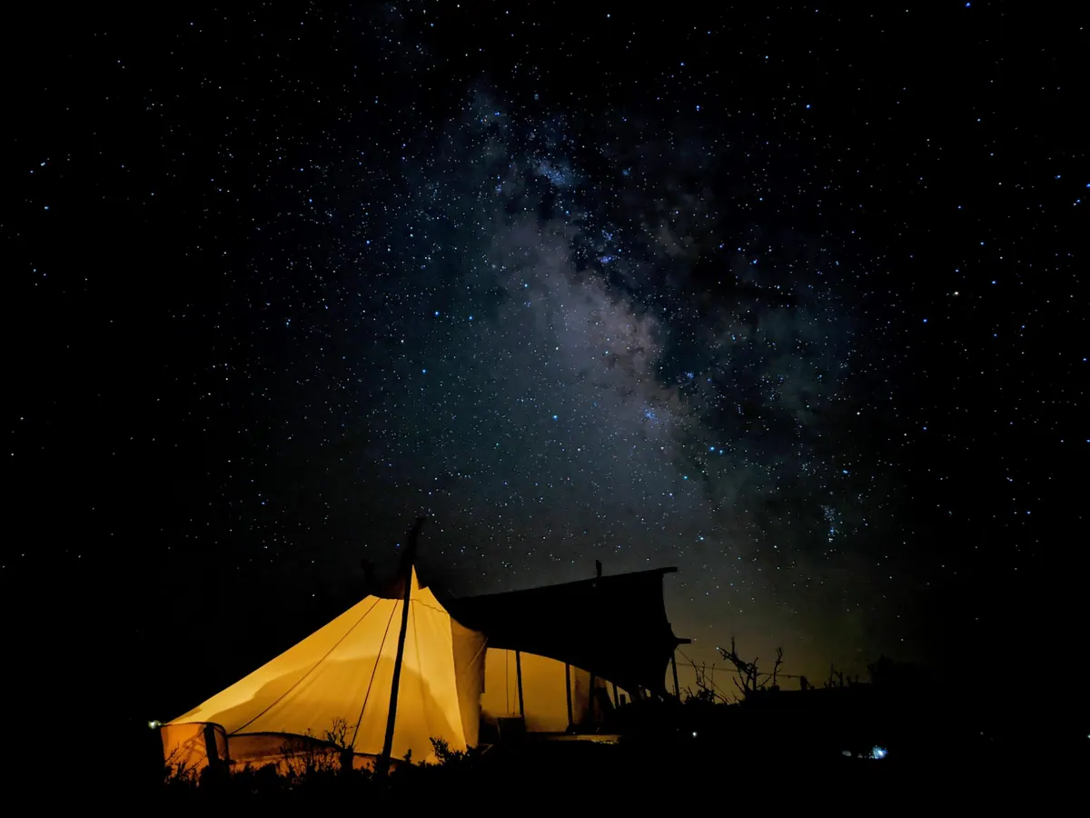 The Milky Way arcing over a lone glamping tent