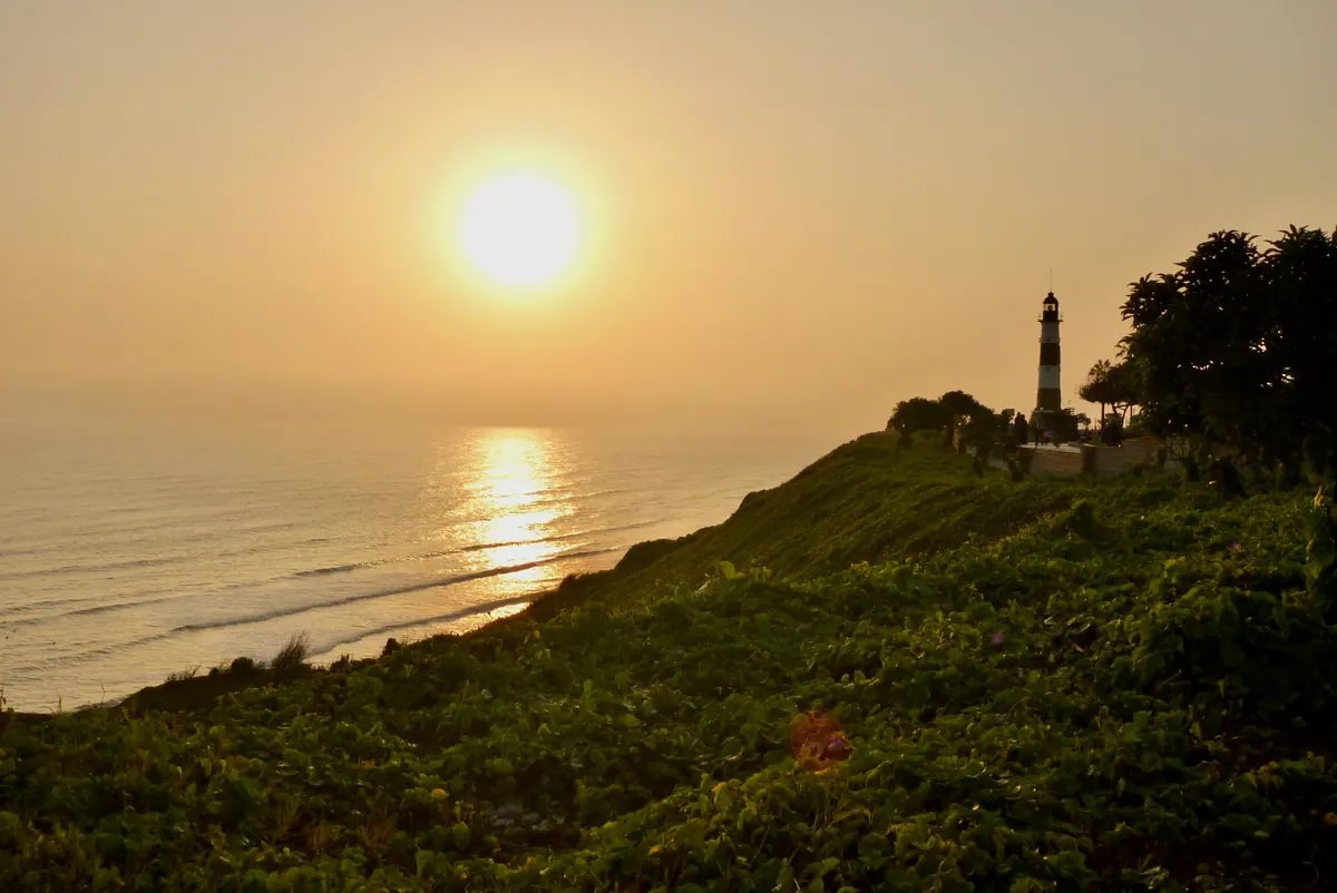 The sun setting into the Pacific beside the Miraflores lighthouse