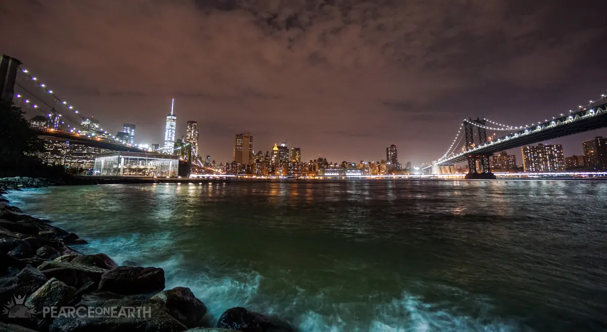 The Manhattan skyline framed by the Brooklyn and Manhattan bridges after dark