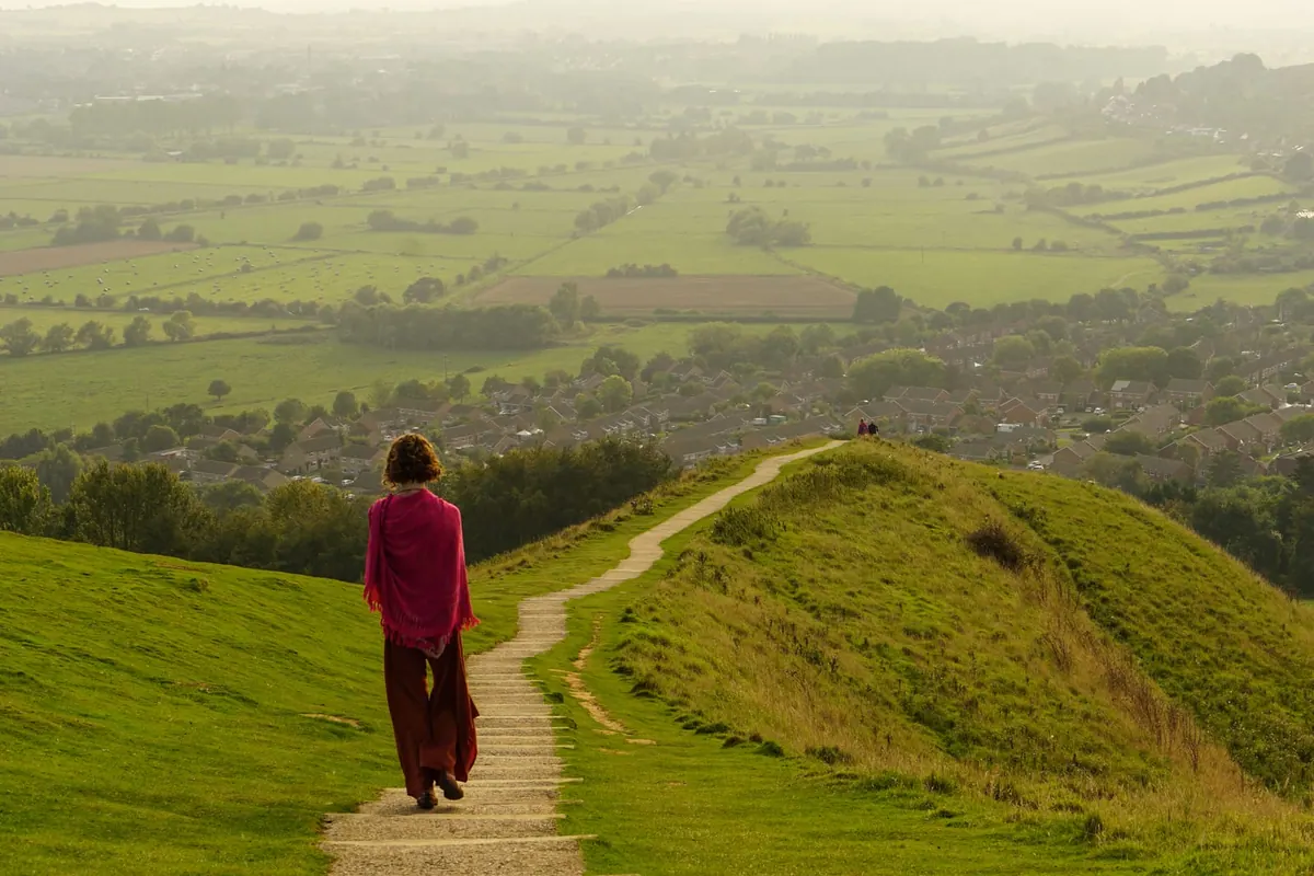 A lone walker on a hilltop path under a wide sky