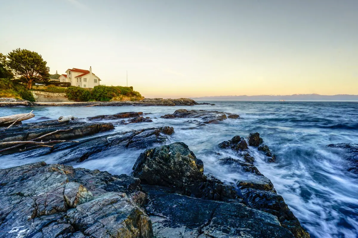 Long-exposure surf washing over dark rocks at sunset